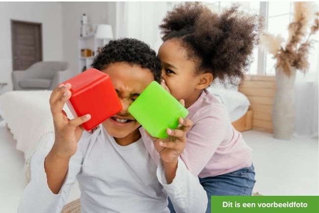 broer en zus spelen met rode en groene kubus. Jongen houdt kubussen voor zijn gezicht